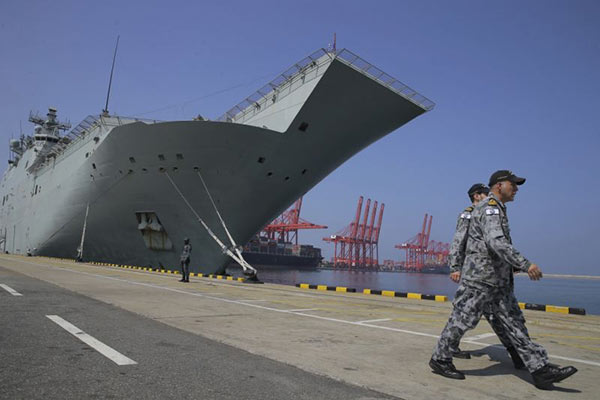 Australian naval officers walk past the HMAS Canberra