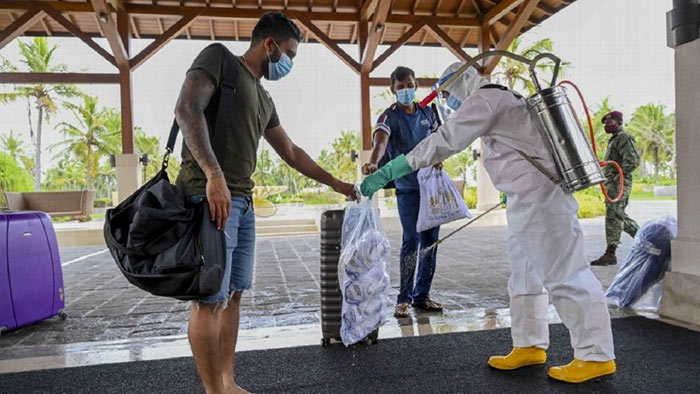 Sri Lanka Cricketer Kusal Mendis collects a package from a PPE-clad hotel staff