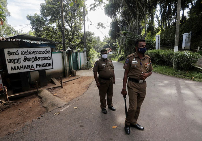 Sri Lankan police officers stand guard at the entrance to the Mahara prison in Sri Lanka