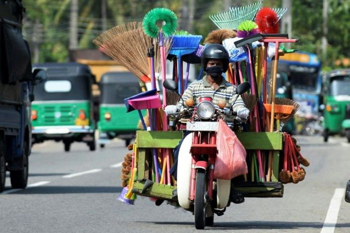 A street vendor selling houseware drives his motorcycle in Colombo, Sri Lanka