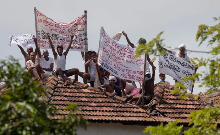 Death-row inmates of Sri Lanka's Welikada prison protest holding banners from the roof of the prison in Colombo, Sri Lanka