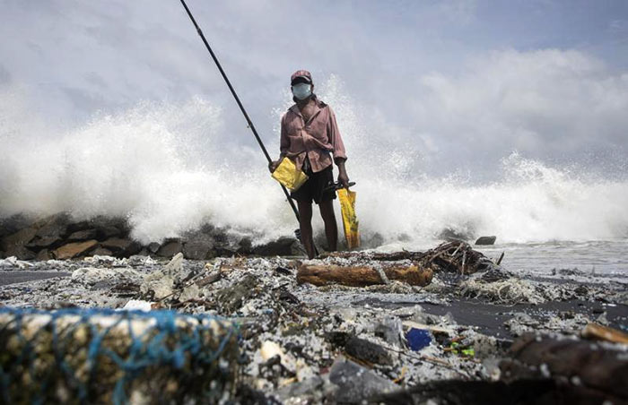 Sri Lankan man fishes on a polluted beach filled with plastic pellets