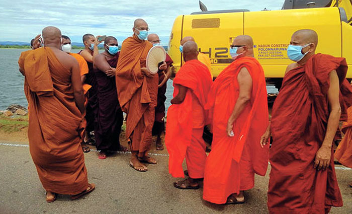 Buddhist monks stand against Parakrama Samudra walking path