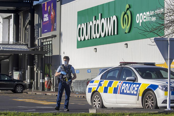 Armed police stand outside a supermarket in Auckland, New Zealand