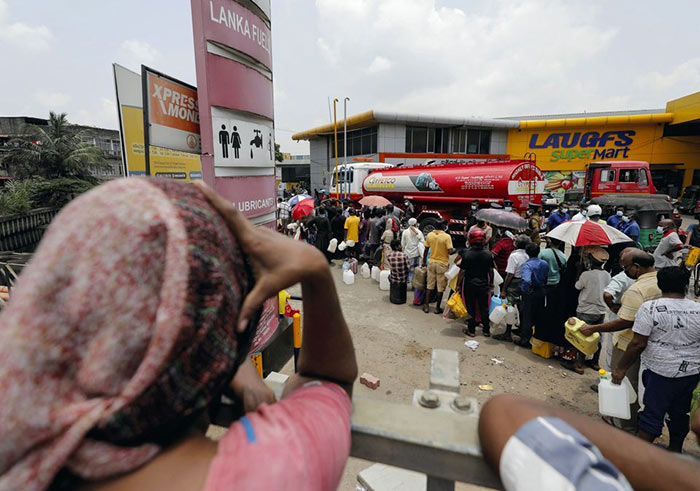 People stand in a long queue to buy kerosene oil at a fuel station in Colombo, Sri Lanka