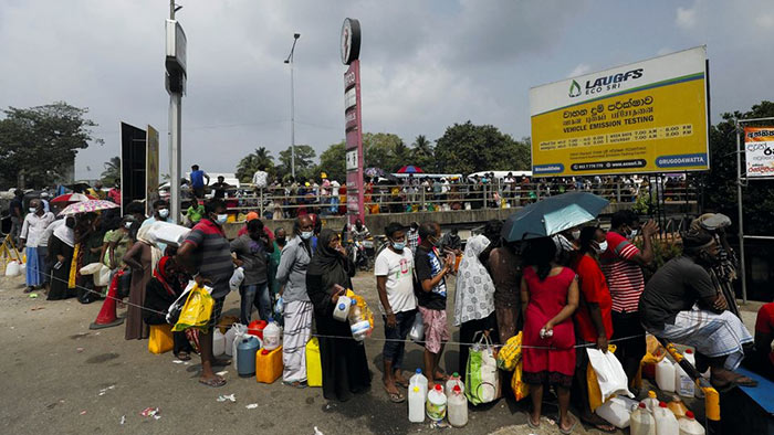People stand in a long queue to buy kerosene oil at a fuel station in Colombo Sri Lanka