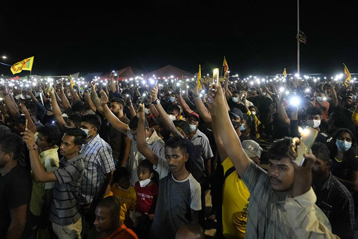Sri Lankans hold up their mobile phone torches during a vigil condemning police shooting at protesters in Rambukkana