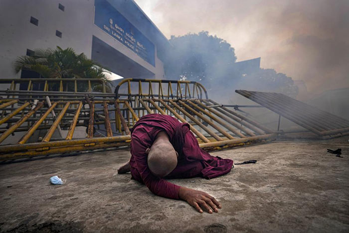 A buddhist nun falls after inhaling tear gas during a protest in Colombo, Sri Lanka