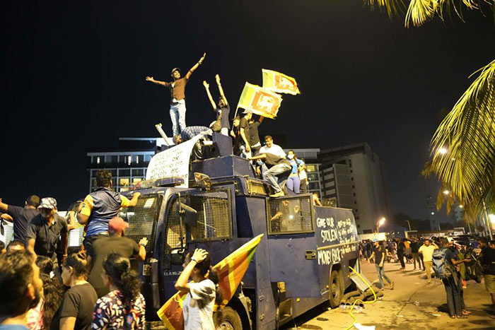 Sri Lankan protesters stand on a vandalised Police water canon truck in Colombo Sri Lanka