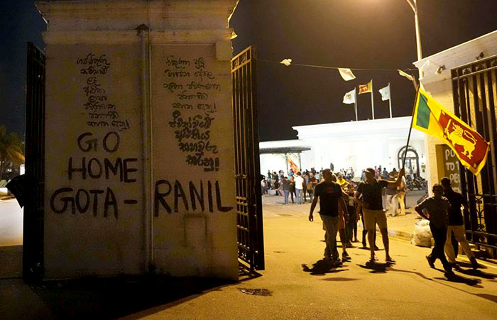 Sri Lankan protesters walk past a vandalised security gate at the President's House in Colombo Sri Lanka