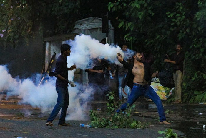 Sri Lankan university student throws back a tear gas canister