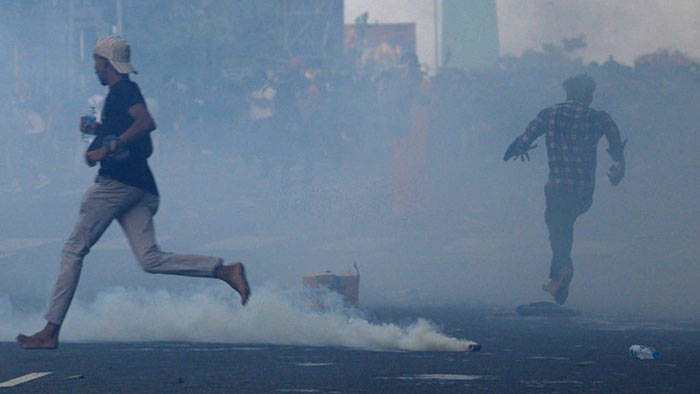 Sri Lankan university students run away after tear gas was fired by Sri Lanka Police during a protest