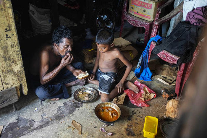 A father and son share a meal at their shanty in Colombo, Sri Lanka