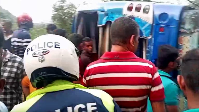 Overturned bus surrounded by people after accident in Dunhinda, Sri Lanka