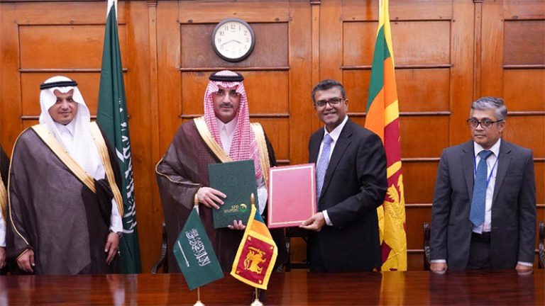 Officials from Sri Lanka and the Saudi Fund for Development display signed agreement documents to the camera after signing the bilateral loan restructuring deal