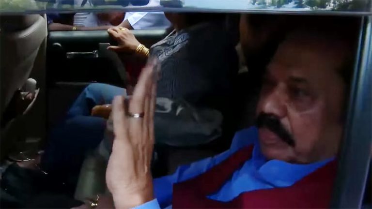 Former Sri Lanka President Mahinda Rajapaksa and his wife seated in the back of a vehicle, waving to the crowd