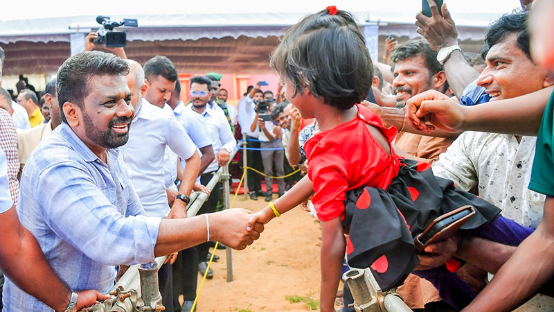 Sri Lanka President Anura Kumara Dissanayake shaking hands with a young girl carried by her father during the Vadduvakal Bridge inauguration