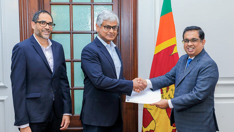 Krishan Balendra hands over donation cheque to Dr. Nandika Sanath Kumanayake, with Gihan Cooray standing nearby