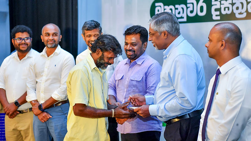 Sri Lanka President Anura Kumara Dissanayake looks on as an official hands over a compensation cheque to a Cyclone Ditwah victim