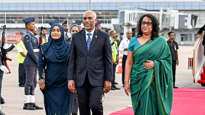 Maldivian President Mohamed Muizzu walks with First Lady Sajidha Mohamed and Sri Lankan Prime Minister Harini Amarasuriya after arriving in Sri Lanka