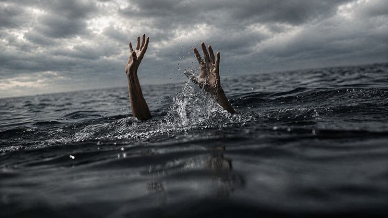 Drowning person’s hands reaching above rough sea waves under a dark cloudy sky - Drown