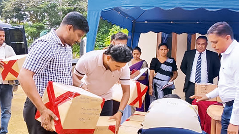 Heroin haul packed in cardboard boxes being sorted before destruction as officials watch in Puttalam