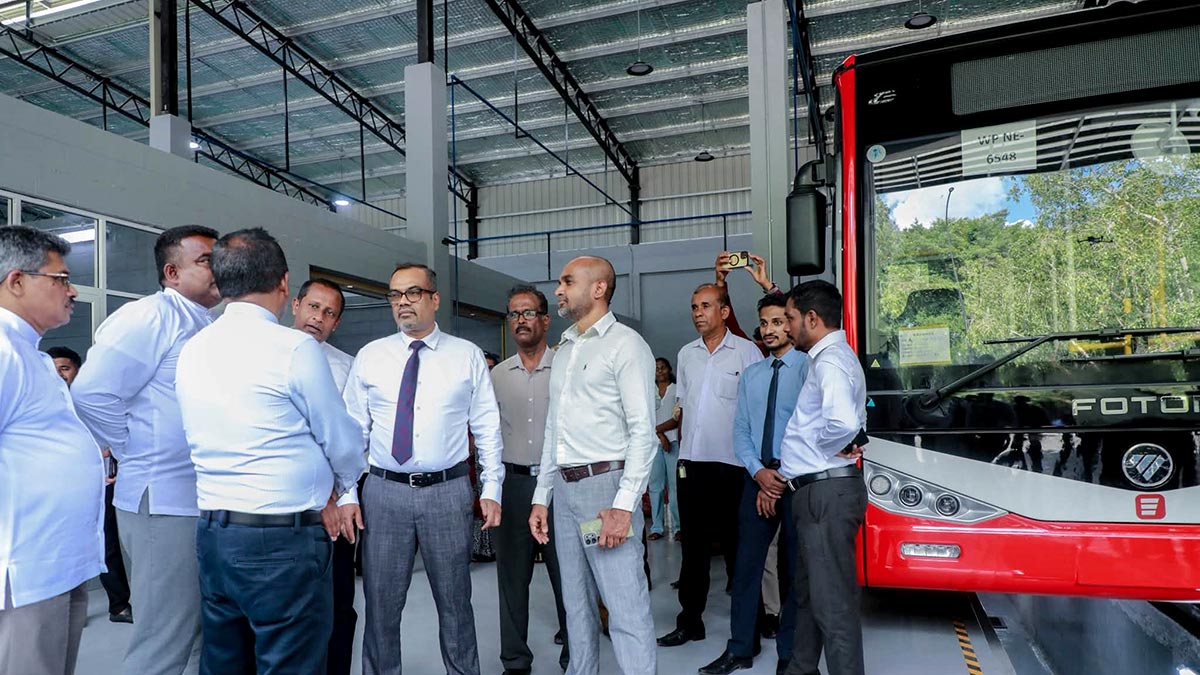 Deputy Minister Prasanna Gunasena, Minister Anil Jayantha and officials at the Ekala Metro Bus depot, with a Metro bus in the background