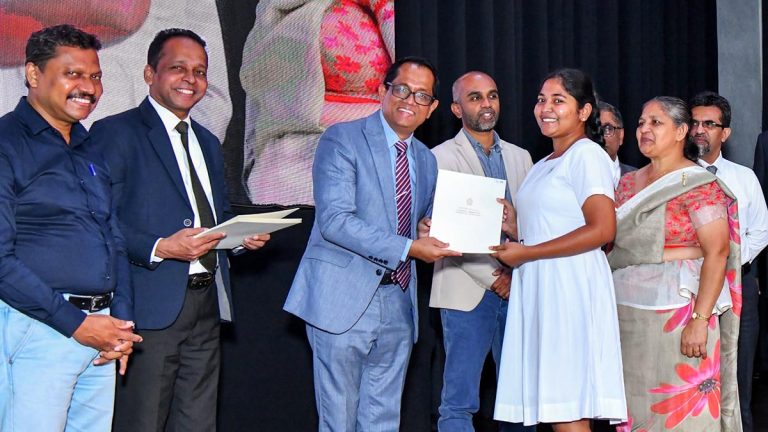 Speaker Dr Jagath Wickramaratne presents a scholarship to a female student at the President’s Fund scholarship programme in Kandy as deputy ministers and other officials look on