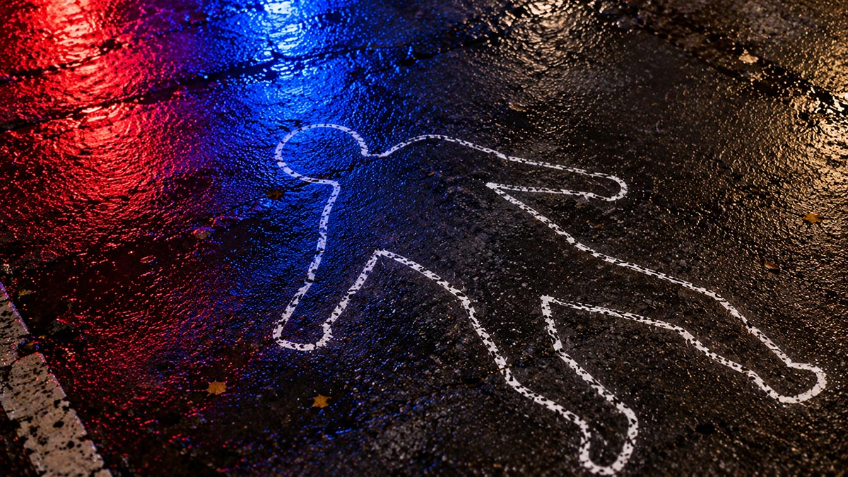 White chalk body outline on wet ground reflecting red and blue police lights